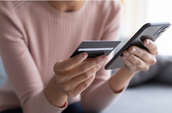 A person holding a mobile phone and bank card